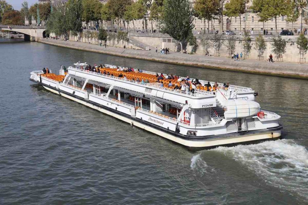 A white tour boat cruises down a wide river.